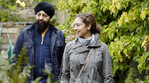 A close-cropped image of two visitors enjoying the garden at Fenton House and Garden; they are surrounded by greenery and a brick wall is visible in the background.